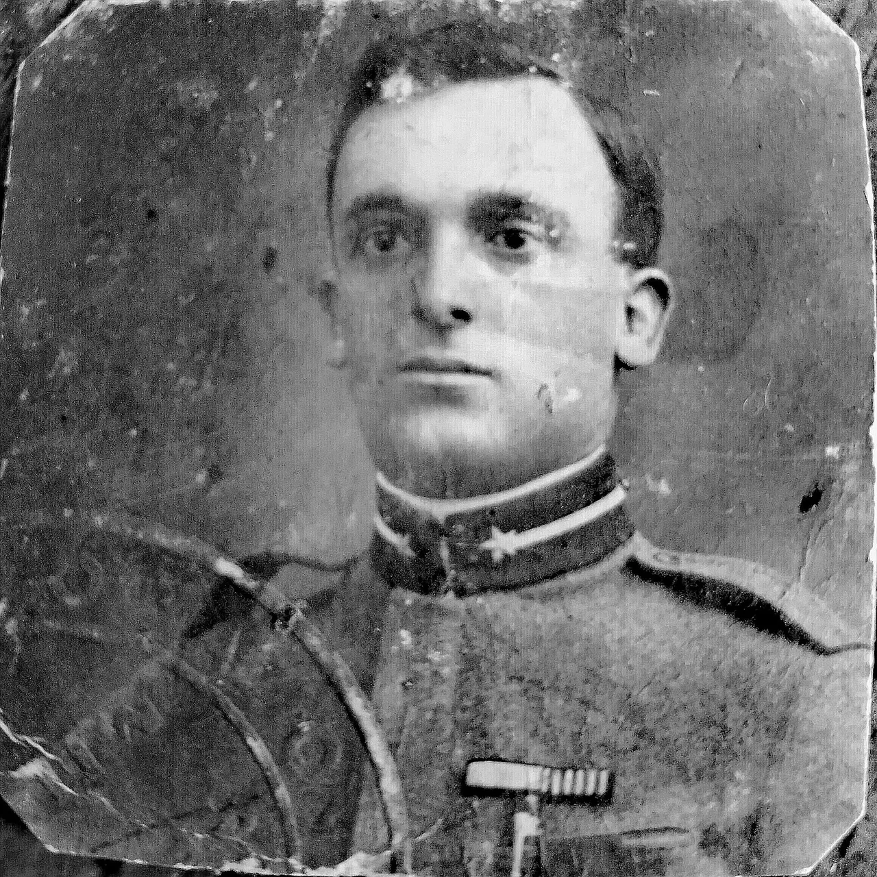 A grey portrait of an infantry soldier with a crease across his face, spots and a chipped corner
